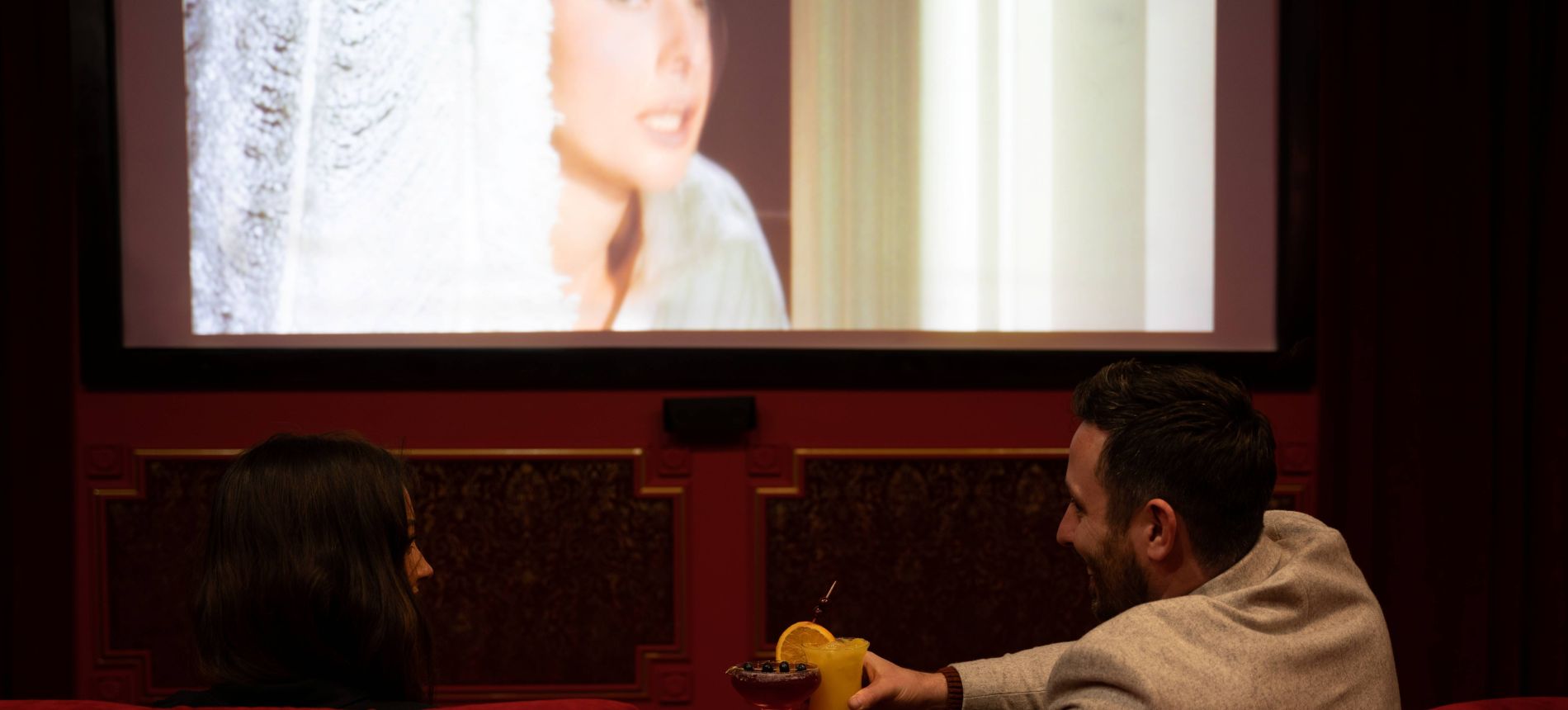 Couple in cinema cheers with cocktails